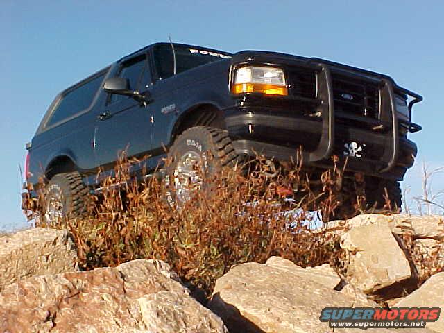 Black 1995 Ford Bronco on rocks, front bull bar, off-road tires