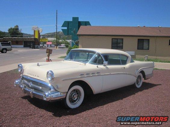 Two-tone cream and white 1950s Buick parked on gravel lot