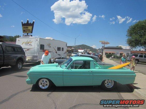 Teal 1960 Ford Falcon Ranchero with a surfboard in the bed parked on a street