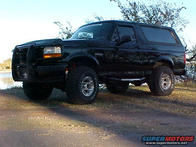Black 1995 Ford Bronco with a bull bar and lifted suspension parked on a dirt road