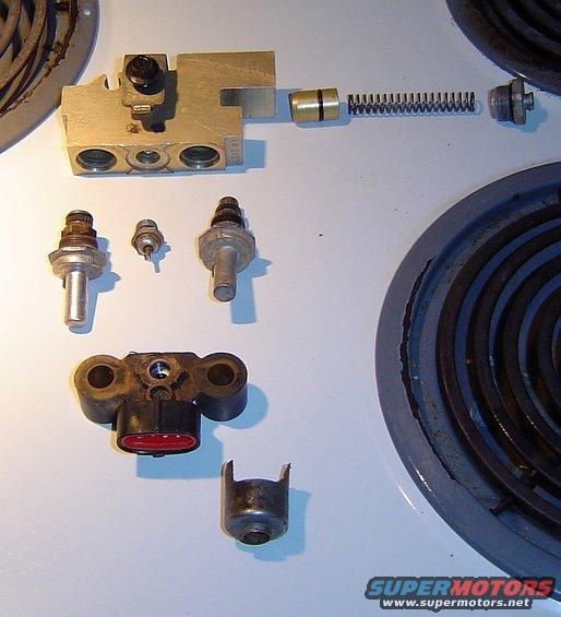 Brake proportioning valve, pressure differential switch, and other small brake system parts laid out on a stovetop