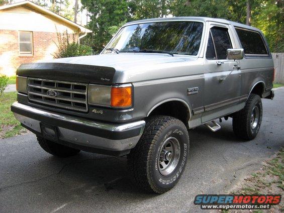 Silver Ford Bronco with grey trim, parked on a paved driveway. Has 'SPORT' badge on the side
