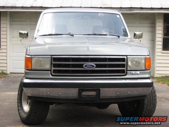 Silver Ford Bronco front view, parked in front of a garage