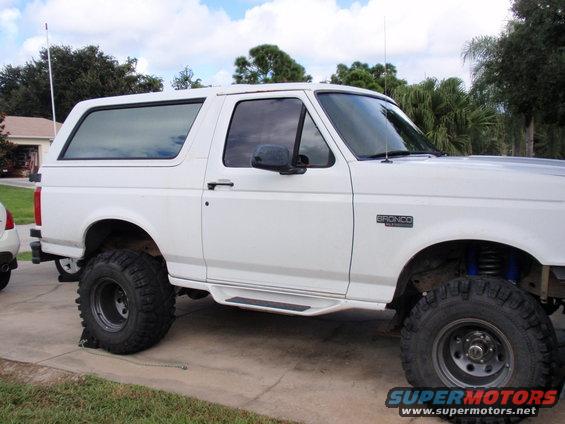 White 1995 Ford Bronco with aftermarket wheels and tires, lifted suspension