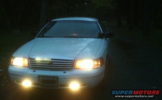 White 1998 Ford Crown Victoria front view with headlights on