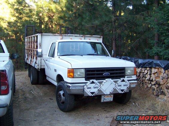 White Ford F-series truck with utility bed parked next to another truck. License plate 3M62237