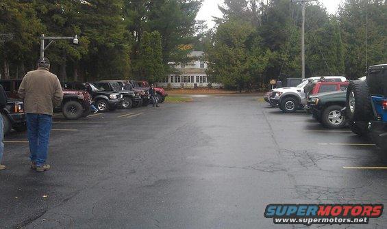 Several SUVs parked in a lot with a building and trees in the background