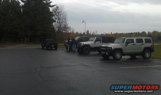Silver Hummer H3 and white Jeep parked in a lot with a black pickup truck