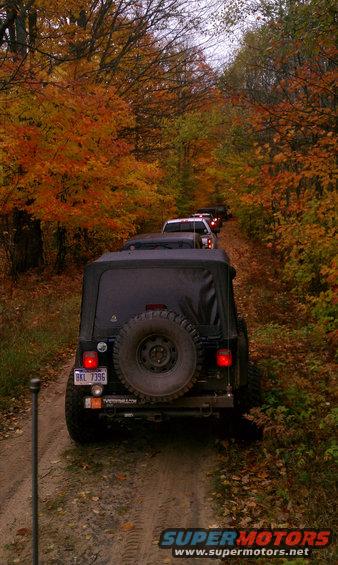 Line of Jeeps driving on a dirt road surrounded by fall foliage