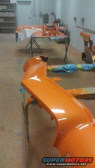 Orange car bumper on stand in workshop