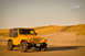 2004 Jeep TJ - A yellow 2004 Jeep TJ sits on a sandy beach with tall grass dunes behind it.