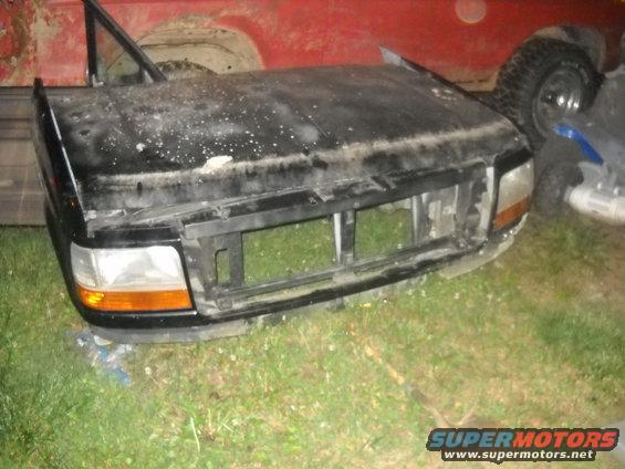 black ford truck front clip, hood, grille, and headlights. red truck behind it