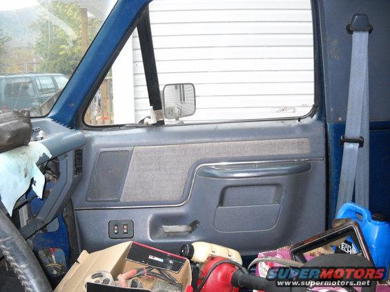 Inside of a blue truck's cab, showing the door panel, seat, and items on the floor