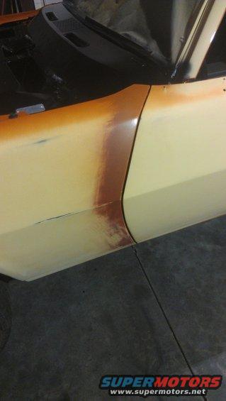 Yellow car fender and door with primer and rust marks, viewed from the side