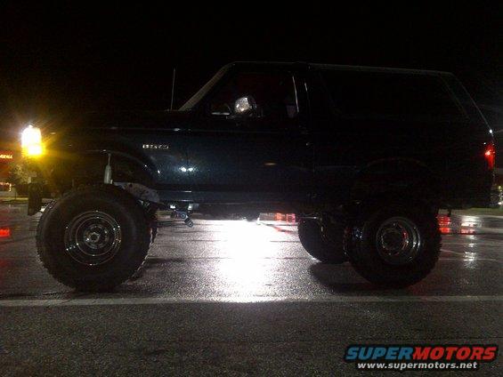 1995 Ford Bronco lifted with large off-road tires, parked at night