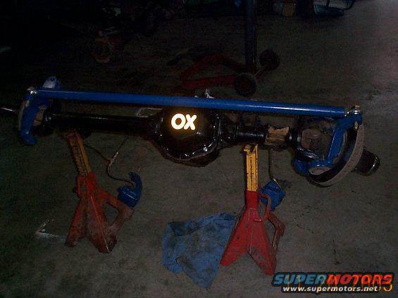 Rear axle assembly with blue sway bar, marked 'OX', on red jack stands