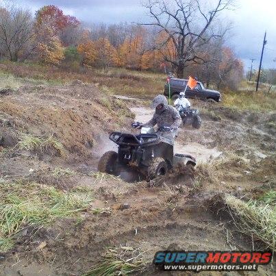 ATVs navigating a muddy track with a dark SUV behind