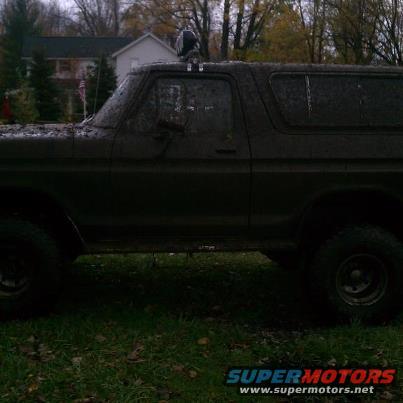 Mud-covered SUV, side view, with a light bar on the roof