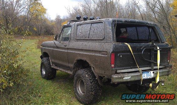 1979 Ford Bronco rear 3/4 view, covered in mud, with roof lights and spare tire carrier