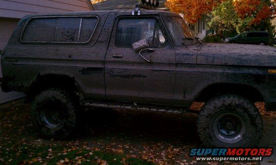 Mud-covered SUV parked in a driveway, with a green van in the background