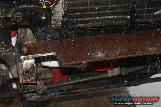 rusted metal plate bolted to vehicle frame near radiator and wiring