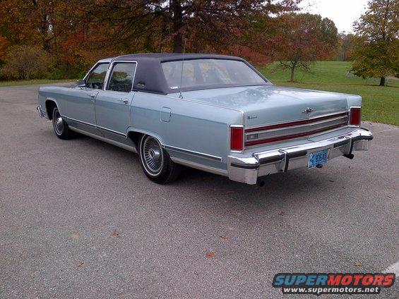 Light blue 1970s Lincoln sedan, rear 3/4 view, black vinyl roof, chrome bumpers