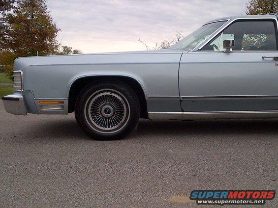 Side view of a light blue sedan with chrome trim and wire wheels