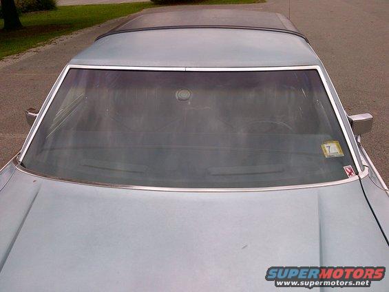 Top-down view of a light blue sedan's windshield and hood. A sticker with the number 7 is on the windshield