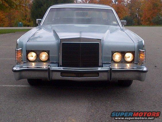 Front view of a light blue Lincoln Continental Mark V with its headlights on