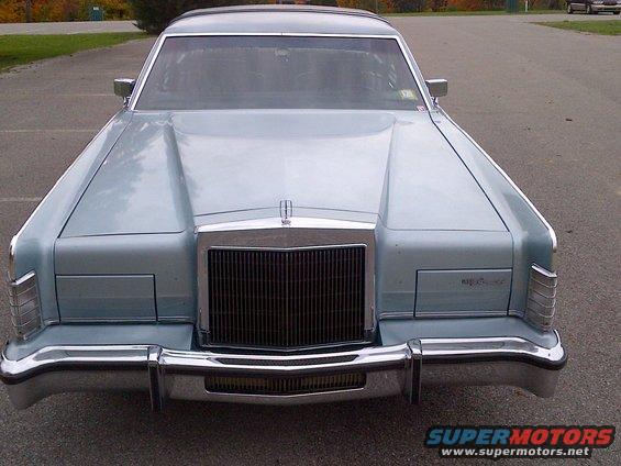 Light blue Lincoln Continental sedan, front view, chrome grille and bumpers, some damage on front bumper