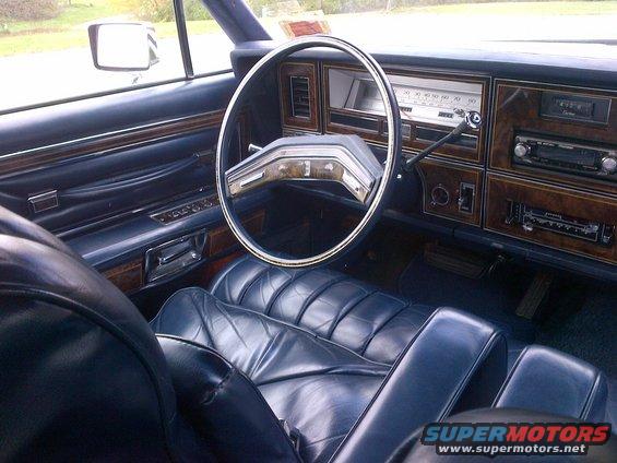 Blue leather seats and wood trim inside a car. Steering wheel and dashboard visible