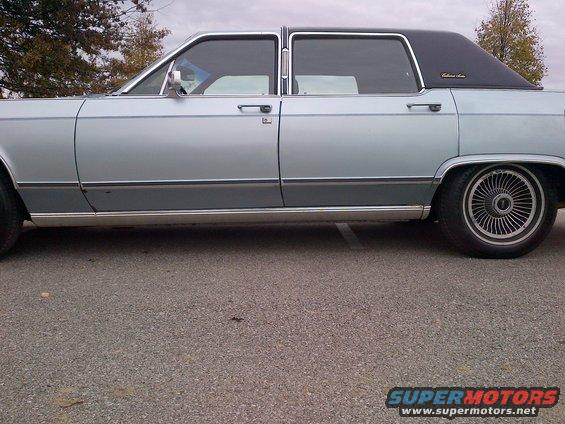 Side view of a light blue and gray 1980s Lincoln Town Car with a black vinyl roof
