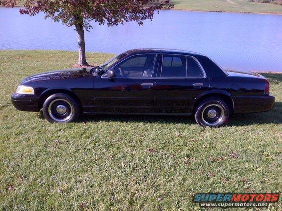 Black 2001 Ford Crown Victoria parked on grass by a lake