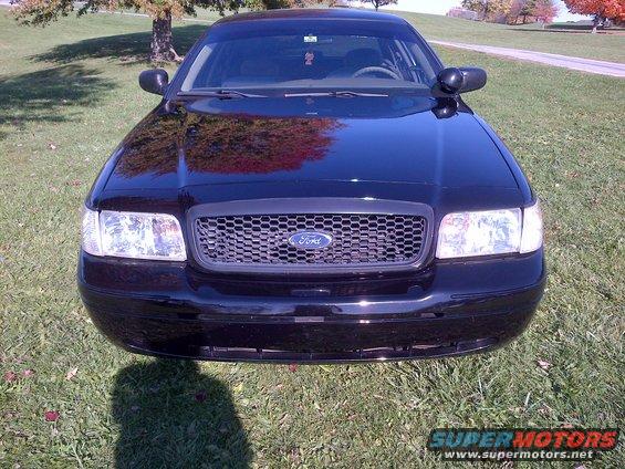 Black 2001 Ford Crown Victoria front view, parked on grass with trees in background