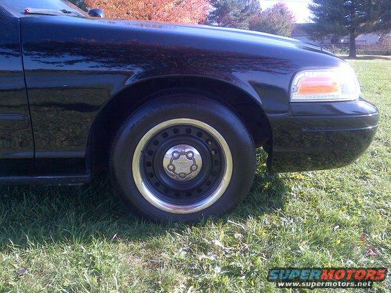 Front fender and wheel of a black 2001 Ford Crown Victoria parked on grass