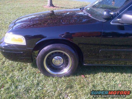 2001 Ford Crown Victoria front fender, headlight, and steel wheel on grass
