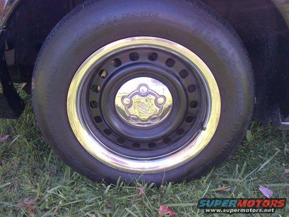 Close-up of a Ford wheel with a chrome trim ring and a Ford logo center cap. The tire has some text on it