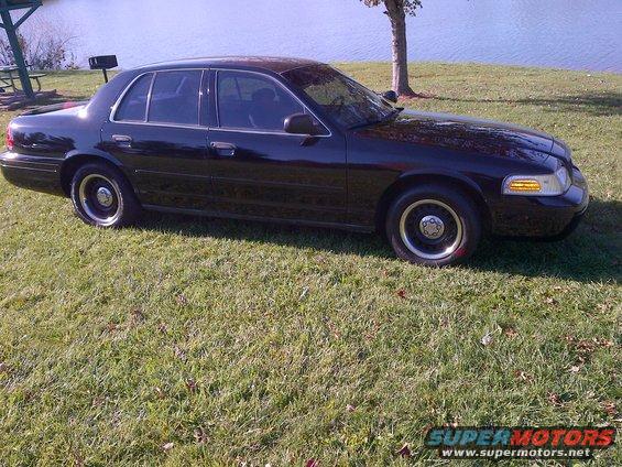 Black 2001 Ford Crown Victoria parked on grass by a lake, side view