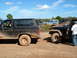 1986 Ford Bronco - A muddy 1986 Ford Bronco is parked next to other off-road vehicles under a blue sky.