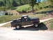 1986 Ford Bronco - This 1986 Ford Bronco is parked on a dirt road with a house and trees in the background.