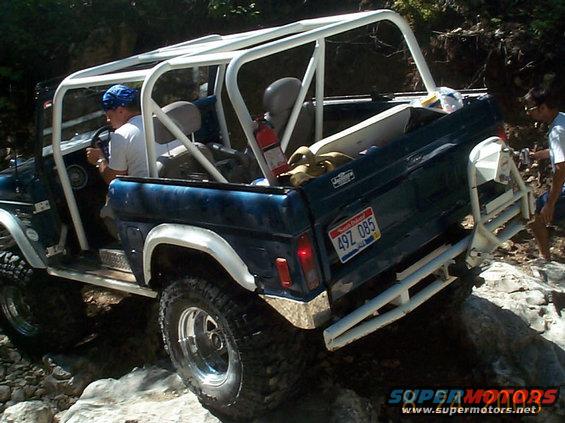 Blue SUV with roll cage driving over rocks. License plate reads 497 085