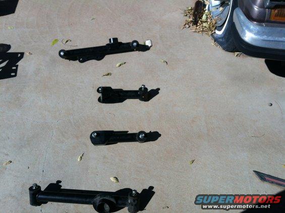 Four black car suspension components on concrete