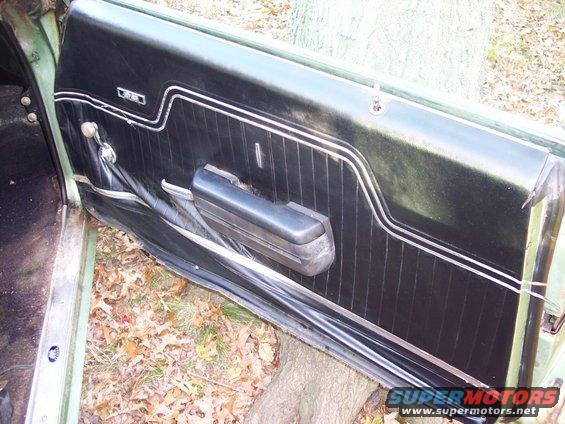 Interior door panel with black vinyl and chrome trim, showing armrest and window crank