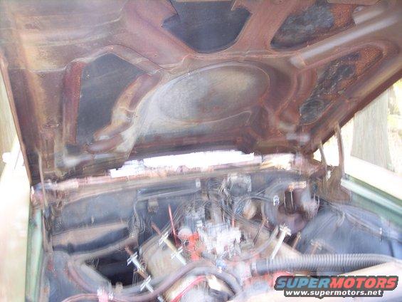 Rusty hood underside and engine bay of a car, viewed from above