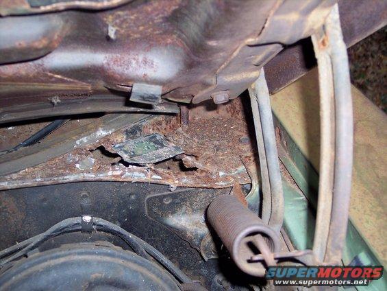 close-up of rusted metal and a spring in a car's engine bay