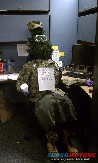 Mannequin in military uniform with a Christmas tree head and goggles, holding a cup