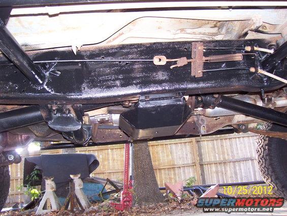 Undercarriage of a 1990 Ford Bronco on jack stands, showing frame, driveshaft, and suspension components