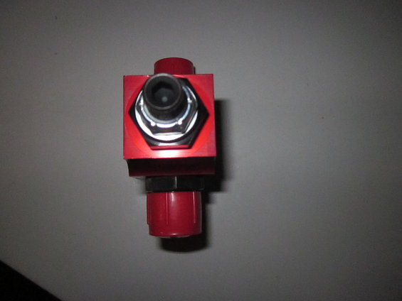 Red anodized aluminum part with hexagonal bolt and red plastic cap, against a gray background