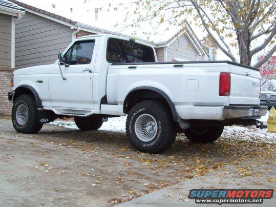 White pickup truck, 3/4 front view, with aftermarket wheels and side steps