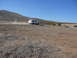 1988 Ford Bronco - A white 1988 Ford Bronco kicks up dust as it drives along a barren dirt road under a clear blue sky.